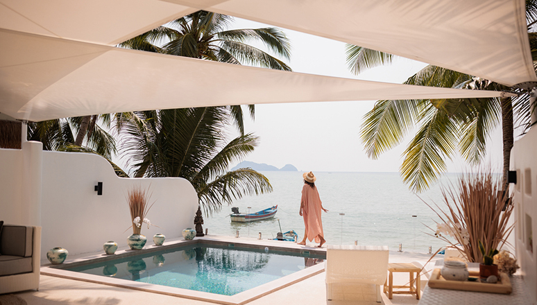 Woman enjoy a leisurely moment by the swimming pool at a luxurious villa on the beach.
