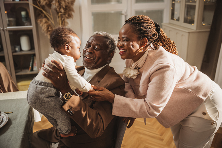 Proud Grandfather Cuddling Baby Grandson at family dinner party