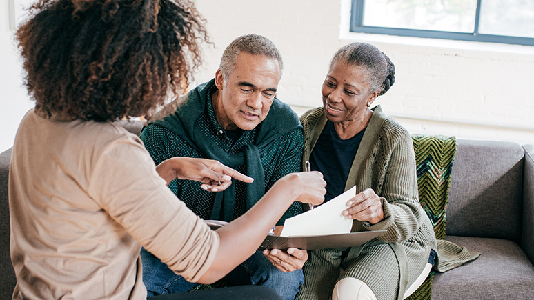 three people having a discussion while looking at a piece of paper
