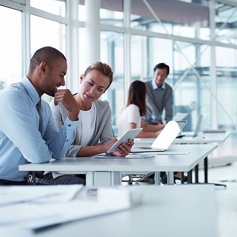 Business colleagues discussing over digital tablet at desk in office