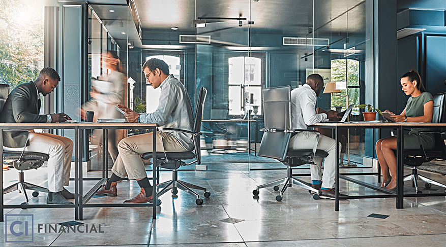 Collègues de travail assis près de leur rangées de bureaux dans un bureau lumineux