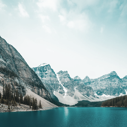 Lac bleu près des arbres et des montagnes enneigées par beau temps