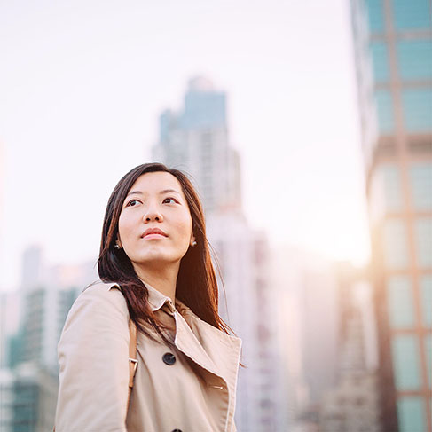 
Jeune femme asiatique regardant avec le sourire par un beau matin contre les toits de la ville