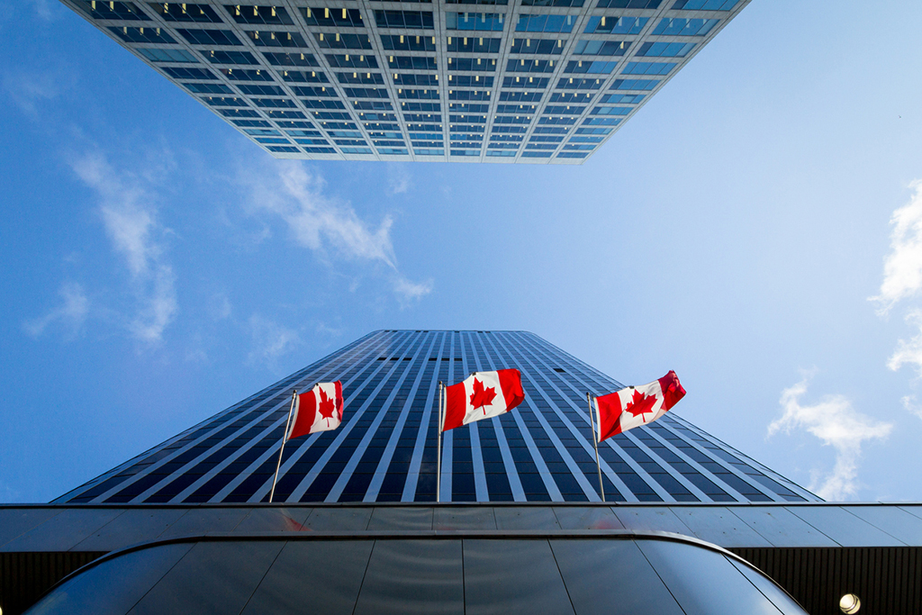 Three Canadian flags in front of a business building in Ottawa, Ontario, Canada.