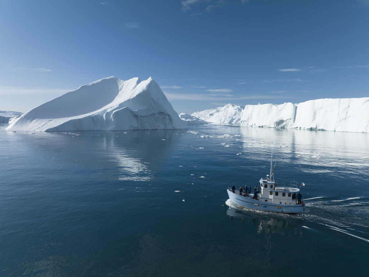 boat sailing between big icebergs from aerial view