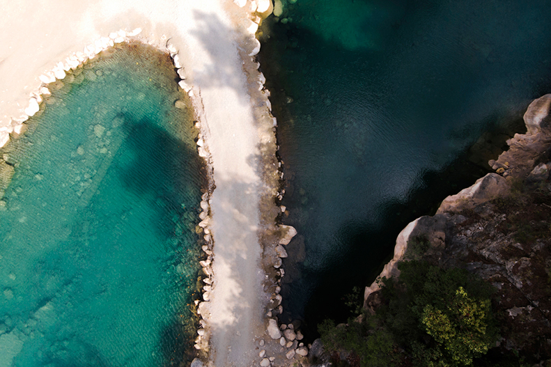 Top view of azure lake with pathway. Beautiful water body captured from drone. Aerial view of picturesque landscape with crystal clear pond. Summer vacation concept. Wild nature paradise