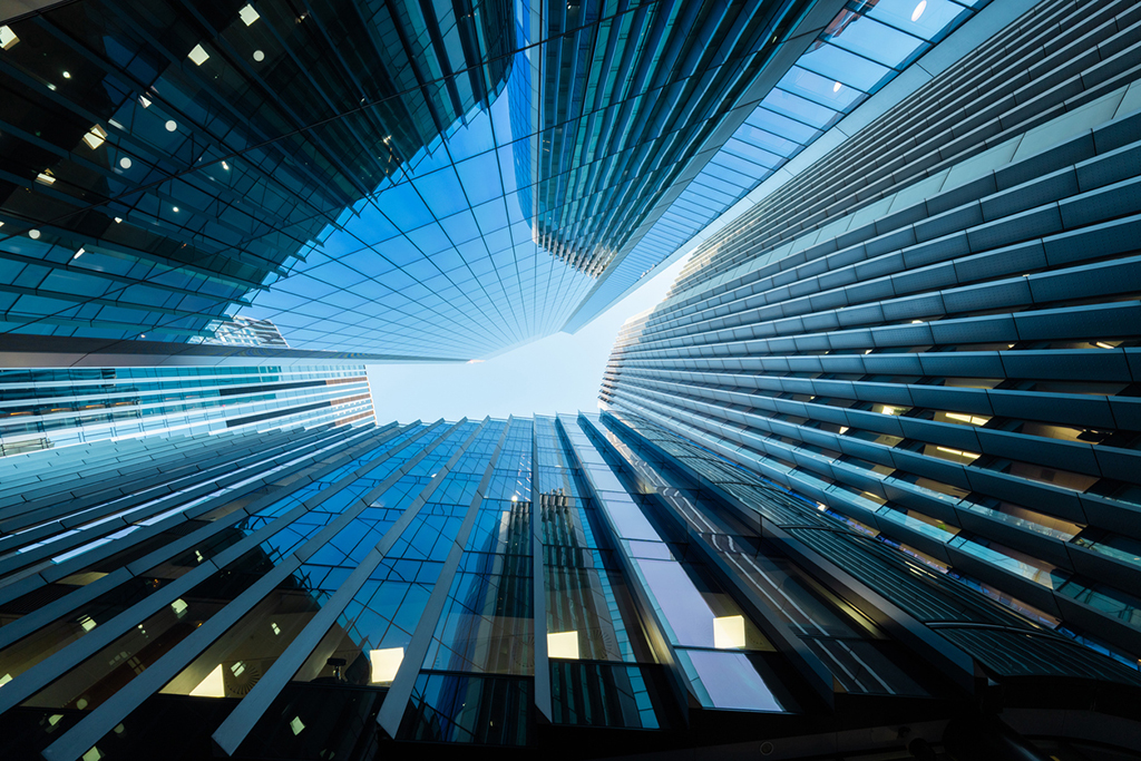 Modern glass skyscrapers reaching towards a clear blue sky in the city of london